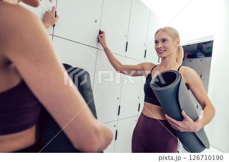 Women in sportswear with the rolled yoga mats looking excited 126710190