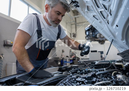 Mechanic inspecting engine with flashlight Mechanic inspecting engine with flashlight 126710219