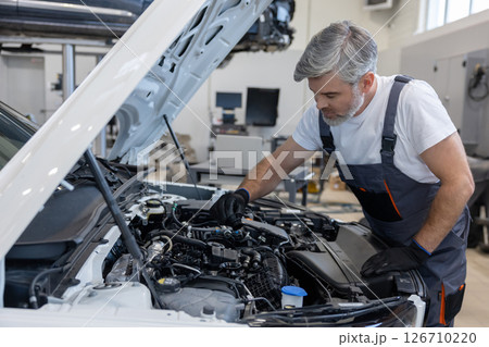 Mechanic checking engine oil in workshop 126710220