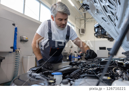 Mechanic checking oil level in engine Mechanic checking oil level in engine 126710221