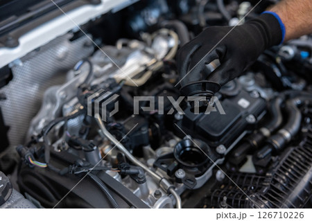 Mechanic checking engine oil in workshop Mechanic checking engine oil in workshop 126710226