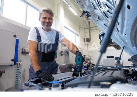 Mechanic working on engine with power drill Mechanic working on engine with power drill 126710229