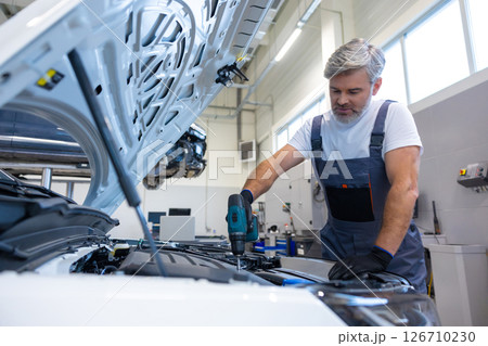 Mechanic using power drill on engine 126710230