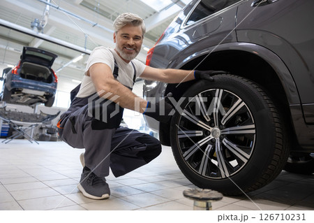 Mechanic checking vehicle wheel 126710231