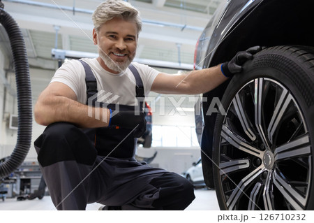 Mechanic examining wheel in workshop 126710232