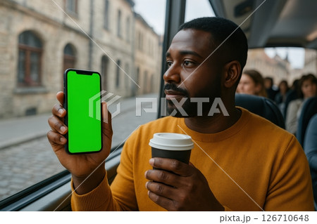 Man holding smartphone with green screen and coffee cup while riding bus. Urban street view through window. Concept of mobile app, travel, commute, tech and morning routine. Copy space. Banner. 126710648
