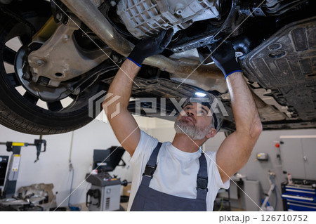 Mechanic with headlamp under vehicle 126710752