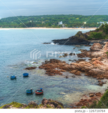 Landscape with Vietnamese round basket boats floating in sea next to the rocks. Da Da reef or Ganh Da Dia in Phu Yen province in Vietnam. Aerial top view from drone 126710764