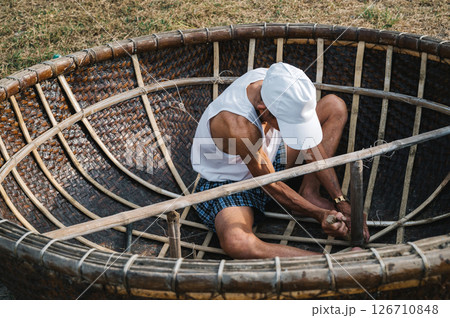 Vietnamese male fisherman craftsman makes traditional round Vietnamese bamboo basket boat Thung Chai 126710848
