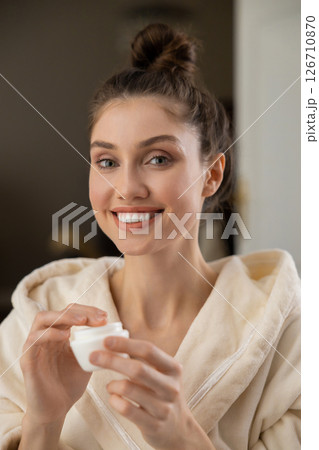 Young woman doing self-care facial routine with organic skincare products 126710870