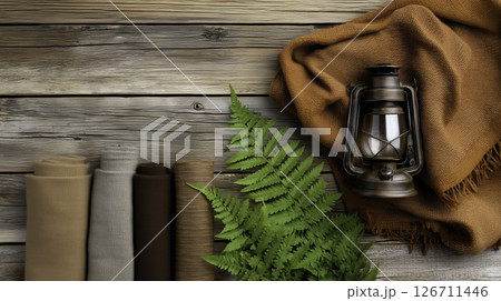 Camping gear arranged on wood with forest textures and natural light. Styled for slow travel and eco-living themes 126711446