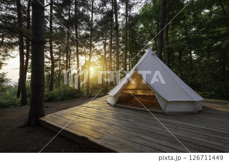 Scenic glamping site with canvas tent, wooden deck, and rustic elements. Tranquil eco-friendly concept in natural forest setting. 126711449