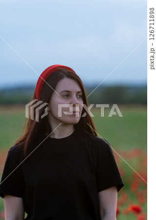 Young Woman in Poppy Field with Red Hat 126711898