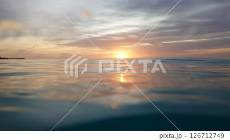 Golden sunrise reflecting on calm ocean water 126712749