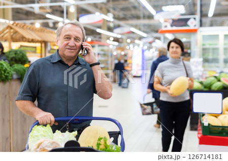 Elderly man talking on mobile phone in supermarket 126714181