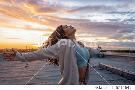 Embracing Freedom at Sunset: Rooftop Serenity Amidst Urban Skyline Silhouette 126714649