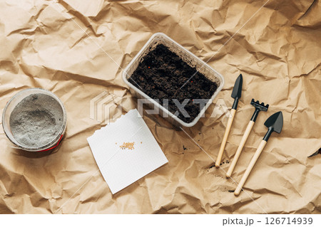 Kraft paper background, fertile soil and garden tools on top, top view. Planting seedlings in spring 126714939