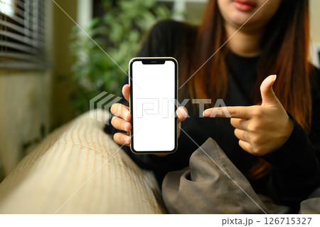 Woman pointing at smartphone with blank display ready for digital content showcase 126715327
