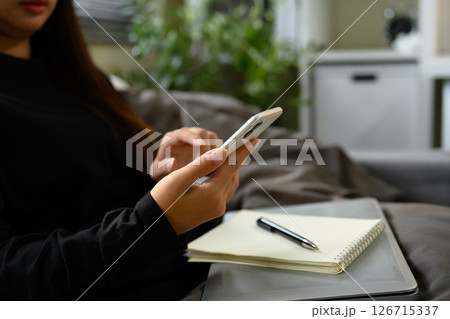 Close up of woman hands using smartphone on sofa at home 126715337