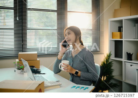 Young business owner communicating with client and drinking coffee at modern workplace Young business owner communicating with client and drinking coffee at modern workplace 126715397