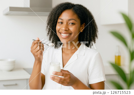 Young African American woman enjoying a healthy yogurt in kitchen, healthy lifestyle 126715523