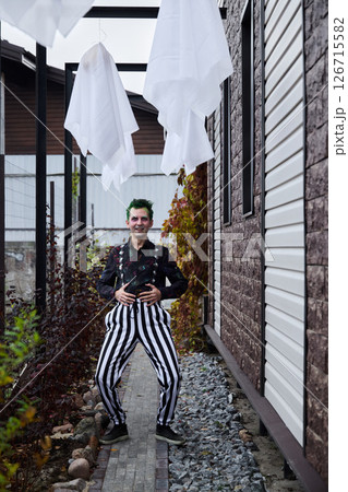 A Whimsical Clown in Colorful Striped Pants Surrounded by Ghostly Decorations and Festive Elements 126715582