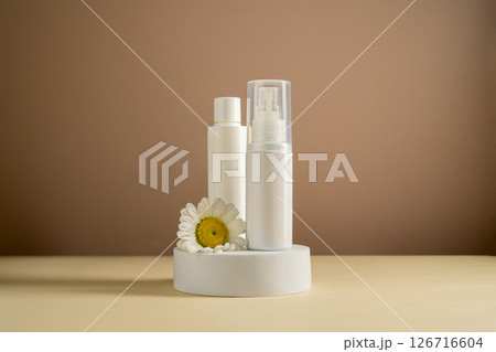 White blank cosmetic bottles with a daisy flower. Natural cosmetics, neutral background 126716604