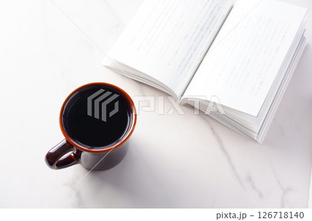 テーブルの上の開いた本とコーヒーカップで、コーヒーを飲みながら読書を楽しんでいるイメージ テーブルの上の開いた本とコーヒーカップで、コーヒーを飲みながら読書を楽しんでいるイメージ 126718140