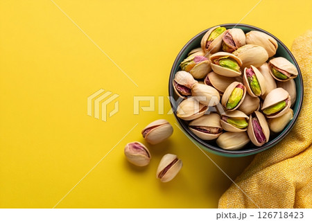 tempting pistachio nuts in the industrial corner on a pastel yellow background tempting pistachio nuts in the industrial corner on a pastel yellow background 126718423