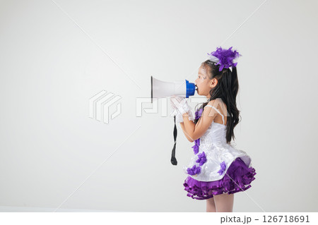 Cheerleader girl in a purple and white outfit using a megaphone. Studio shot on white background, showcasing her energetic, festive, and spirited vibe. A fun portrait of a young cheerleader. Cheerleader girl in a purple and white outfit using a megaphone. Studio shot on white background, showcasing her energetic, festive, and spirited vibe. A fun portrait of a young cheerleader. 126718691