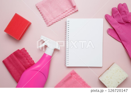 Pink cleaning supplies including rubber gloves, spray bottle, microfiber cloths. Household cleaning and hygiene concept. Mock up notebook 126720147