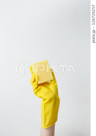 Hand in yellow rubber glove holding a sponge for cleaning. Household cleaning and hygiene concept concept 126720257