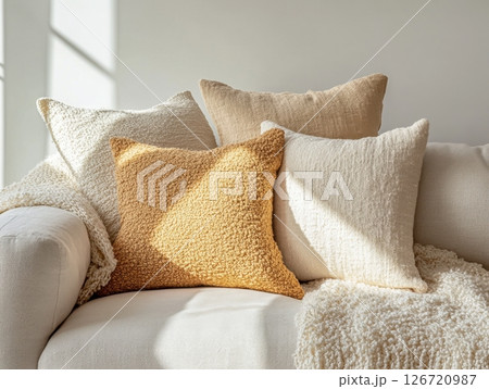 Cozy minimalist living room featuring soft boucle fabric throws and pillows on a sleek sofa, with an eco-friendly atmosphere 126720987