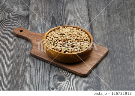Green lentils in wooden bowl on wooden table background. Top view, copy space. Flat lay. Green lentils in wooden bowl on wooden table background. Top view, copy space. Flat lay. 126721918