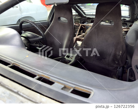 Old sport car interior with worn bucket seats, stripped rear section and roll cage installation, showcasing restoration stage before final rebuild and customization 126722356