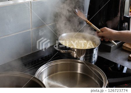 Cooking Pasta on the Stove with Steam Rising Up, Creating an Inviting Atmosphere in the Kitchen 126723774