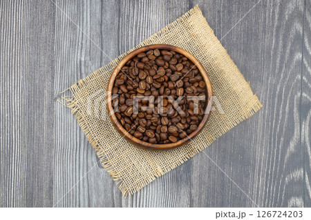 Wooden bowl with coffee beans on wooden background Wooden bowl with coffee beans on wooden background 126724203