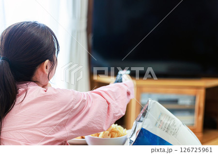 スナック菓子を食べながらテレビを見る女性 126725961