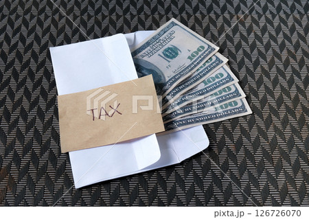 Cash Dollars money in envelope with note written TAX. 126726070