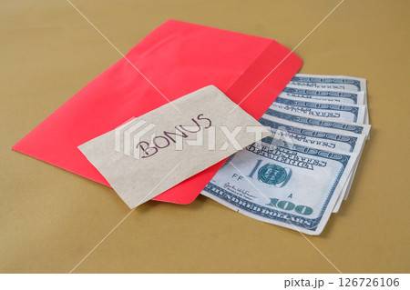Cash Dollars money in red envelope with note written BONUS , concept bonus reward for employee and staff. Cash Dollars money in red envelope with note written BONUS , concept bonus reward for employee and staff. 126726106
