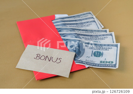 Cash Dollars money in red envelope with note written BONUS , concept bonus reward for employee and staff. Cash Dollars money in red envelope with note written BONUS , concept bonus reward for employee and staff. 126726109