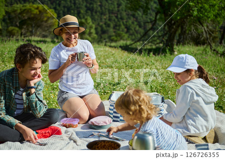 Family Sharing a Joyful Picnic Outdoors in a Peaceful Mountain Setting Family Sharing a Joyful Picnic Outdoors in a Peaceful Mountain Setting 126726355