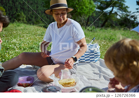 Mother Enjoying a Family Picnic in the Mountains on a Sunny Summer Day Mother Enjoying a Family Picnic in the Mountains on a Sunny Summer Day 126726366