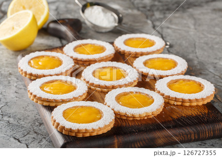 Shortbread cookies with lemon crud filling sprinkled with powdered sugar closeup on wooden board. Horizontal 126727355