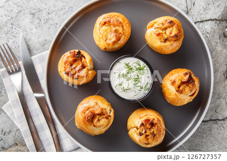 Knish is a delicious potato stuffed pies served with sour cream close-up in a plate. Horizontal top view Knish is a delicious potato stuffed pies served with sour cream close-up in a plate. Horizontal top view 126727357