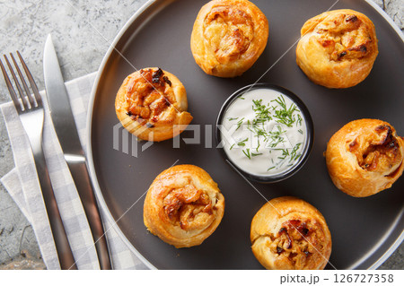 Ukrainian Knysh are pies with onion and potato filling served with sour cream close-up in a plate. Horizontal top view Ukrainian Knysh are pies with onion and potato filling served with sour cream close-up in a plate. Horizontal top view 126727358