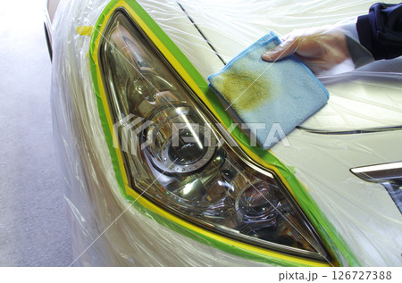 経年劣化で変色したヘッドライトの表面をクリーナーで磨いたマイクロファイバークロスが黄土色に汚れた様子 126727388