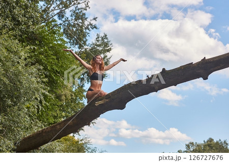 Girl sitting high up on a fallen tree 126727676
