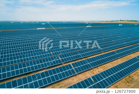 Expansive solar panel arrays under a clear blue sky in a vast renewable energy farm 126727800