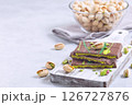 Milk chocolate bar with pistachio and kadaifi filing, lying on cutting board, horizontal copy space 126727876